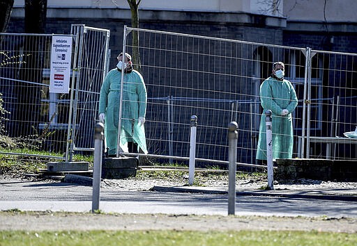 Medical staff stand at the entrance to the Outpatient Diagnostic Centre of the Coronavirus Diagnostic Unit at the Koepenick Hospital in Berlin, Monday, March 23, 2020. In order to slow down the spread of the coronavirus, the German government has considerably restricted public life and asked the citizens to stay at home. For some people the new COVID-19 coronavirus causes only mild or moderate symptoms, but for some it can cause severe illness including pneumonia. Britta Pedersen/dpa via AP)