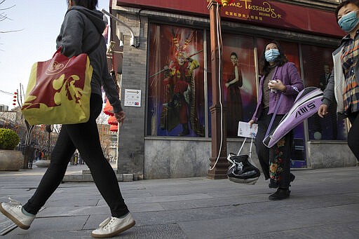 Residents walk through a quiet retail district in Beijing on Monday, March 23, 2020. Even while social distancing and quarantines for new arrivals remain the norm, China is striving to restore activity in the world's second-largest economy after the shutdown over the coronavirus outbreak. (AP Photo/Ng Han Guan)