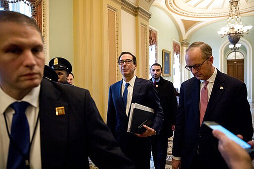 Treasury Secretary Steven Mnuchin, center, and White House Legislative Affairs Director Eric Ueland, right, walk to the offices of Senate Majority Leader Mitch McConnell of Ky., on Capitol Hill in Washington, Monday, March 23, 2020, as the Senate is working to pass a coronavirus relief bill. (AP Photo/Andrew Harnik)