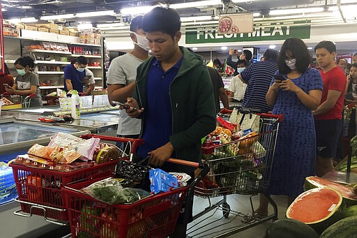 People line up to buy food and other supplies at a 24-hour supermarket in Yangon, Myanmar, Tuesday, March 24, 2020, following the first cases of coronavirus announcement. Myanmar has announced its first two confirmed cases of COVID-19, one in the nation's biggest city, Yangon, and the other in the western state of Chin. For most people, the new coronavirus causes only mild or moderate symptoms. For some it can cause more severe illness. (AP Photo/Thein Zaw)