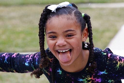 Sydney Grimes, 7, sticks her tongue out to catch a snowflake outside their Chicago neighborhood on Sunday, March 22, 2020. Her mom says she's less aware than her older sister of the effect the new coronavirus is having on their lives and is enjoying the time at home, for now. Their parents worry about the impact on both their girls. (AP Photo/Martha Irvine)