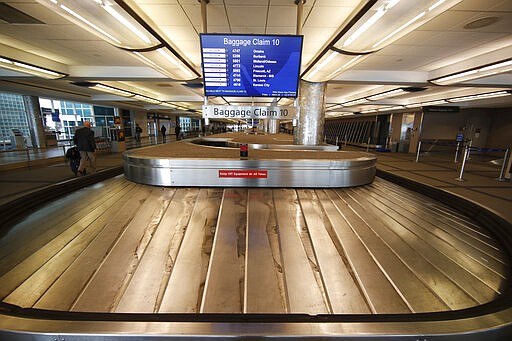 FILE - In this March 20, 2020 file photo, an empty baggage carousel spins in Denver International Airport as travelers deal with the spread of the coronavirus  in Denver.  Airline service in the United States is teetering on the brink of collapse, with near-empty planes and coronavirus-caused outbreaks that have left some air traffic control towers empty. Even with sharply reduced schedules, airlines are consolidating some of the remaining flights because passengers aren&#146;t showing up. (AP Photo/David Zalubowski, File)