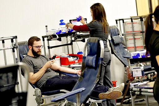 Jeff Maxwell prepares to donate blood at a temporary blood bank set up in a church's fellowship hall Tuesday, March 24, 2020, in Tempe, Ariz. Schools and businesses that typically host blood drives are temporarily closed due to precautionary measures in place to reduce the spread of the COVID-19 coronavirus leading to extremely low levels of blood availability throughout the state. (AP Photo/Matt York)