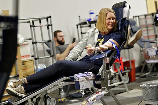 Mandy Kershaw looks towards her son as they donate blood at a temporary blood bank set up in a church's fellowship hall Tuesday, March 24, 2020, in Tempe, Ariz. Schools and businesses that typically host blood drives are temporarily closed due to precautionary measures in place to reduce the spread of the COVID-19 coronavirus leading to extremely low levels of blood availability throughout the state. (AP Photo/Matt York)