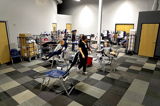 People donate blood at a temporary blood bank set up in a church's fellowship hall Tuesday, March 24, 2020, in Tempe, Ariz. Schools and businesses that typically host blood drives are temporarily closed due to precautionary measures in place to reduce the spread of the COVID-19 coronavirus leading to extremely low levels of blood availability throughout the state. (AP Photo/Matt York)