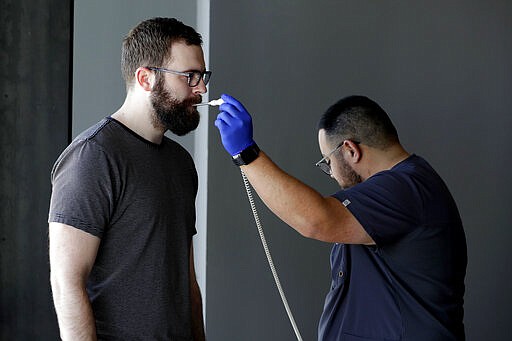 Jeff Maxwell has his temperature taken before being allowed to donate blood at a temporary blood bank set up in a church's fellowship hall Tuesday, March 24, 2020, in Tempe, Ariz. Schools and businesses that typically host blood drives are temporarily closed due to precautionary measures in place to reduce the spread of the COVID-19 coronavirus leading to extremely low levels of blood availability throughout the state. (AP Photo/Matt York)