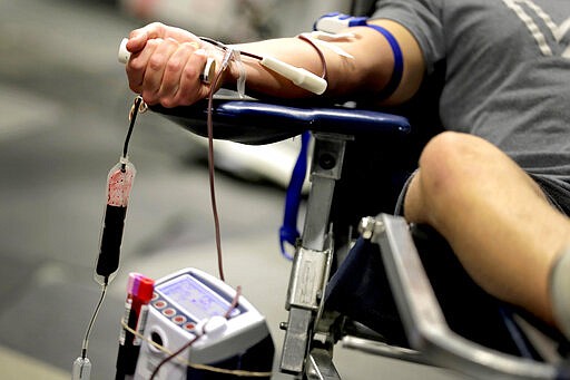 James Kershaw donates blood at a temporary blood bank set up in a church's fellowship hall Tuesday, March 24, 2020, in Tempe, Ariz. Schools and businesses that typically host blood drives are temporarily closed due to precautionary measures in place to reduce the spread of the COVID-19 coronavirus leading to extremely low levels of blood availability throughout the state. (AP Photo/Matt York)