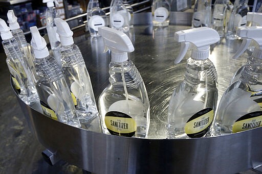 Bottles of hand sanitizer made at Tattersall Distilling Tuesday, March 24, 2020 in Minneapolis sit ready for packaging as the company lent an effort to provide the sanitizer, made from a World Health Organization recipe and signed off by the FDA to make available for nursing homes, health centers and first responders fighting the coronavirus. (AP Photo/Jim Mone)