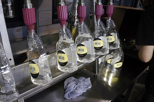 Bottles are filled with hand sanitizer at Tattersall Distilling Tuesday, March 24, 2020 in Minneapolis as the company lent an effort to provide the sanitizer, made from a World Health Organization recipe and signed off by the FDA, to make available for nursing homes, health centers and first responders fighting the coronavirus. (AP Photo/Jim Mone)