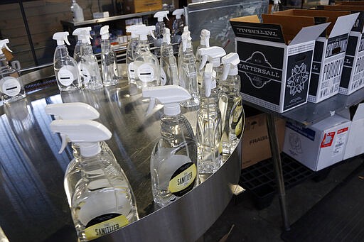 Bottles of hand sanitizer sit ready to be boxed up at Tattersall Distilling Tuesday, March 24, 2020 in Minneapolis as the company lent an hand to provide the sanitizer, made from a World Health Organization recipe and signed off by the FDA, to make available for nursing homes, health centers and first responders fighting the coronavirus. (AP Photo/Jim Mone)