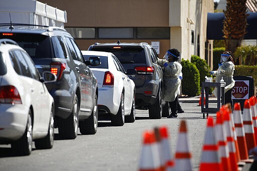 A health care worker with the UNLV School of Medicine tests a patient for the coronavirus at a drive thru testing site Tuesday, March 24, 2020, in Las Vegas. UNLV Medicine, the clinical arm of the UNLV School of Medicine, started conducting COVID-19 testing by appointment for people who meet the Centers for Disease Control and Prevention guidelines. (AP Photo/John Locher)