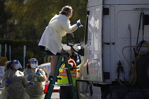 Dr. Elissa Palmer stands on a ladder to test a patient in a truck for the coronavirus at a drive thru testing site Tuesday, March 24, 2020, in Las Vegas. UNLV Medicine, the clinical arm of the UNLV School of Medicine, started conducting COVID-19 testing by appointment for people who meet the Centers for Disease Control and Prevention guidelines. (AP Photo/John Locher)