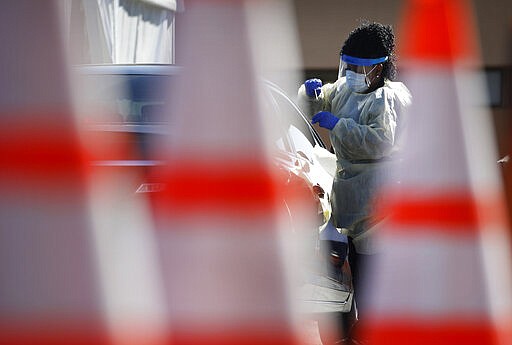 A health care worker with the University of Nevada, Las Vegas School of Medicine tests a patient for the coronavirus at a drive-through testing site Tuesday, March 24, 2020, in Las Vegas. UNLV Medicine, the clinical arm of the UNLV School of Medicine, started conducting COVID-19 testing by appointment for people who meet the Centers for Disease Control and Prevention guidelines. (AP Photo/John Locher)