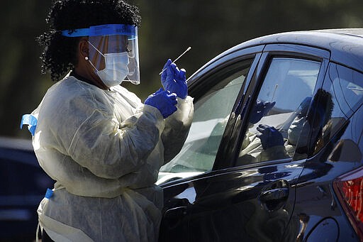 A health care worker with the UNLV School of Medicine tests a patient for the coronavirus at a drive thru testing site Tuesday, March 24, 2020, in Las Vegas. UNLV Medicine, the clinical arm of the UNLV School of Medicine, started conducting COVID-19 testing by appointment for people who meet the Centers for Disease Control and Prevention guidelines. (AP Photo/John Locher)