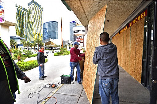 FILE - In this March 18, 2020, file photo, workers install plywood over windows at a souvenir shop along the Las Vegas Strip after all the casinos and non-essential businesses in the state were ordered to shut down due to the coronavirus in Las Vegas. The emerging coronavirus pandemic has spurred a lawsuit by a Las Vegas attorney with a background in big cases, who is seeking compensation from the Chinese government for more than 32 million small U.S. businesses that have lost income and profits as a result of the outbreak. Eglet seeks class-action status and said Tuesday, March 24, 2020 he believes damages for Chinese &quot;reckless&quot; and &quot;negligent&quot; conduct could be in the trillions of dollars. They seek compensation from the government of China. (AP Photo/David Becker, File)