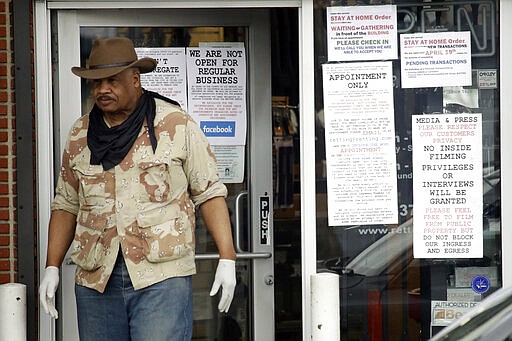 CORRECTS TO CULVER CITY, INSTEAD OF LOS ANGELES An employees stands at the entrance to a guns shop Tuesday, March 24, 2020, in Culver City, Calif. Los Angeles County Sheriff Alex Villanueva said he would like to see gun shops shut down. &quot;We will be closing them, they are not an essential function,&quot; Villanueva said. Adding guns to households where more people are at home during a crisis increases the risk that someone will be shot, he said. (AP Photo/Marcio Jose Sanchez)