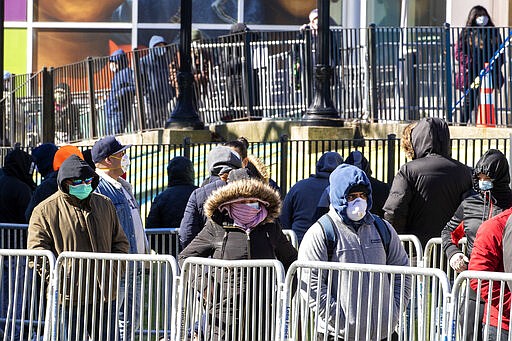 People line up outside Elmhurst Hospital Center to be tested for the coronavirus, Tuesday, March 24, 2020, in the Queens borough of New York. New York Gov. Andrew Cuomo says the number of positive coronavirus cases in the state surged to more than 20,000, with more than half the cases in New York City.  (AP Photo/Mary Altaffer)