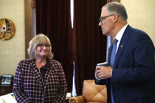 First Lady Trudi Inslee left, looks across at her husband, Gov. Jay Inslee, after the governor spoke about additional plans to slow the spread of coronavirus during a televised address from his office Monday, March 23, 2020, in Olympia, Wash. The latest update from the Washington state Department of Health showed there have been at least 110 coronavirus deaths in the state and more than 2,200 confirmed cases. (AP Photo/Elaine Thompson)