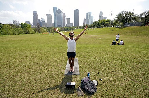 Trey Evans participates in an online yoga class using his laptop and headphones outside at Eleanor Tinsley Park near downtown Houston, Tuesday, March 24, 2020. BIG Power Yoga has been holding online classes during the coronavirus outbreak. A Stay Home - Work Safe Order was issued Tuesday for Houston and Harris County residents to help fight the spread of COVID-19. The order will go into effect at 11:59 p.m. and will last until April 3. Harris County Judge Lina Hidalgo said people should stay home except for essential needs. (AP Photo/David J. Phillip)