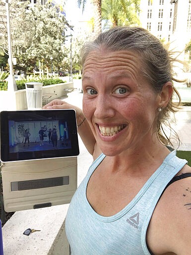 In this selfie provided by Beth Berglin, she shows a screen where she joins a Burn Boot Camp live stream workout from her home Thursday, March 19, 2020, in Coral Gables, Fla. People around the country who are self-isolating or maintaining social distance during the coronavirus outbreak have to think outside the gym when it comes to their fitness routines. Many are turning to online classes or getting outside to exercise.  (Beth Berglin via AP)