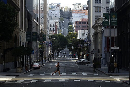 A man runs across a near empty Montgomery Street in San Francisco, March 21, 2020. (AP Photo/Jeff Chiu)