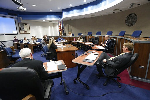 Members of the Lynchburg City Council sit in chairs in front of their normal meeting positions during a meeting, Tuesday March 24 , 2020, in Lynchburg, Va. Officials in Lynchburg said Tuesday they were fielding complaints and concerns about the hundreds of students that have returned from their spring break to Liberty University, where President Jerry Falwell Jr. has welcomed them back amid the coronavirus pandemic. (AP Photo/Steve Helber)