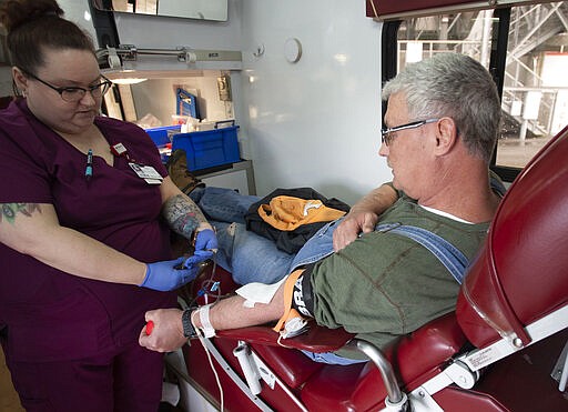 Marsh Regional Blood Center's Tammy Sluder assists Eddie Davidson as he donates blood Monday, March 23, 2020 during a daylong blood drive at Bristol Motor Speedway in Bristol, Tenn. With a nationwide shortage of blood supply growing, the blood drive provides local residents the opportunity to donate in a time of need due to the coronavirus pandemic. (David Crigger/Bristol Herald Courier via AP)