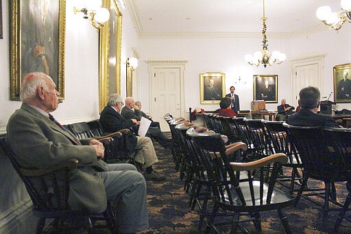 Democratic State Sen. Richard Sears, left, sits apart from others in a meeting room to follow the social distance requirements set by the governor, Tuesday March 24, 2020, at the Statehouse in Montpelier, Vt. The Senate met in its chamber with 17 members, one over the required quorum, to pass legislation needed to confront the coronavirus pandemic. (Paul Heintz/Seven Days via AP, Pool)