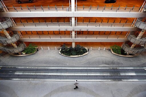 People navigate a deserted parking area at Raleigh Durham International Airport in Raleigh, N.C., Tuesday, March 24, 2020. The coronavirus has impacted travel throughout much of the world leaving many airports void of travelers as many flights are delayed or canceled. (AP Photo/Gerry Broome)