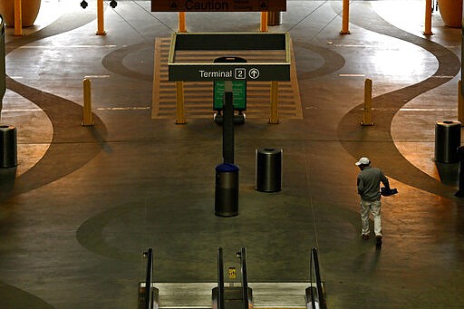 A man walks through a mostly deserted parking garage at Raleigh Durham International Airport in Raleigh, N.C., Tuesday, March 24, 2020. The coronavirus has impacted travel throughout much of the world leaving travelers stranded with canceled or delayed flights. (AP Photo/Gerry Broome)