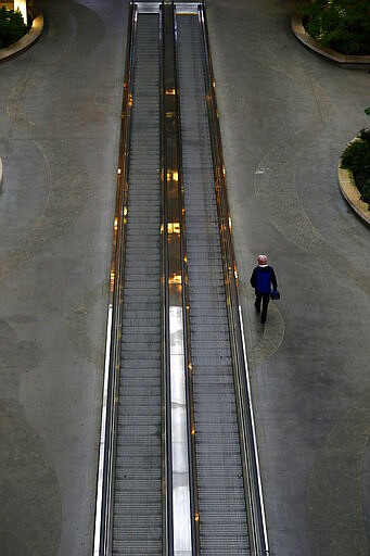 A person walks through a mostly deserted parking garage at Raleigh Durham International Airport in Raleigh, N.C., Tuesday, March 24, 2020. The coronavirus has impacted travel throughout much of the world. (AP Photo/Gerry Broome)