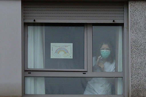 A nurse looks out from a window next to a banner reading in Spanish &quot;Everything is going to be all right&quot; inside of a nursing homes where dead bodies were found at the nursing homes of Usera in Madrid, Spain, Tuesday, March 24, 2020. Spanish army troops disinfecting nursing homes have found, to their horror, some residents living in squalor among the infectious bodies of people that authorities suspect have died from the new coronavirus. Prosecutors have launched a judicial probe. For some, it can cause more severe illness, especially in older adults and people with existing health problems. (AP Photo/Manu Fernandez)