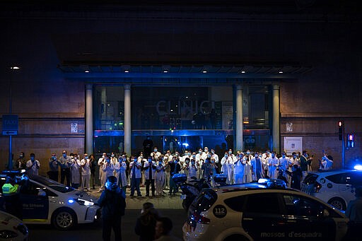 Health workers gather outside the Hospital Clinic joining applause by police officers and residents in support of the medical staff that are working on the COVID-19 virus outbreak in Barcelona, Spain, Monday, March 23, 2020. For most people, the new coronavirus causes only mild or moderate symptoms. For some it can cause more severe illness. (AP Photo/Felipe Dana)