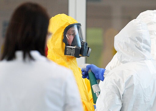 Russian President Vladimir Putin, center, wearing a protective suit visits the hospital for coronavirus patients in Kommunarka settlement, outside Moscow, Russia, Tuesday, March 24, 2020. Putin praised its doctors for high professionalism, saying they were working &quot;like clockwork.&quot;  For some people the COVID-19 coronavirus causes mild or moderate symptoms, but for some it can cause severe illness including pneumonia. (Alexei Druzhinin, Sputnik, Kremlin Pool Photo via AP)