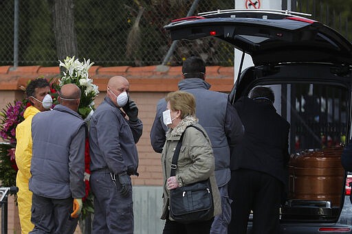 Undertakers carry a coffin of a person who died of COVID-19 at a cemetery in Leganes, Spain, Tuesday, March 24, 2020. For some people the COVID-19 coronavirus causes mild or moderate symptoms, but for some, it can cause severe illness, especially in older adults and people with existing health problems. (AP Photo/Manu Fernandez)