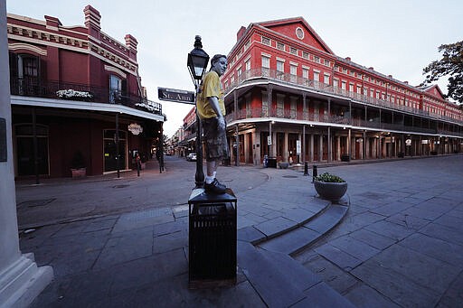 Street performer Eddie Webb looks around the nearly deserted French Quarter looking to make money in New Orleans, Sunday, March 22, 2020. With much of the city already hunkered down due to the coronavirus pandemic, Louisiana Gov. John Bel Edwards issues a shelter-in-place order to take effect starting Monday at 5:00 PM. (AP Photo/Gerald Herbert)