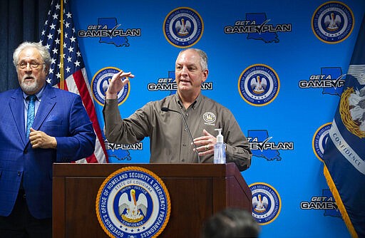 Louisiana Gov. John Bel Edwards, center, speaks about &quot;flattening the curve&quot; of the rate of spread of COVID-19 by limiting contact between people, at a briefing of media members on the state's coronavirus response at a press conference at the Governor's Office of Homeland Security &amp; Emergency Management, Tuesday, March 24, 2020, in Baton Rouge, La. Sign language interpreter Daniel Burch is next to him, left.  (Travis Spradling/The Advocate via AP, Pool)