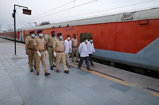 Railway officials walk through a deserted railway station platform in Prayagraj, India, Tuesday, March 24, 2020. Indian Prime Minister Narendra Modi Tuesday announced a total lockdown of the country of 1.3 billion people to contain the new coronavirus outbreak. For most people, the new coronavirus causes only mild or moderate symptoms. For some it can cause more severe illness. (AP Photo/Rajesh Kumar Singh)