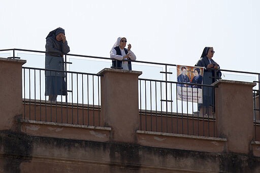 Nuns wait for Pope Francis blessing in St. Peter's Square, at the Vatican, Sunday, March 22, 2020. During his weekly Sunday blessing, held due to virus concerns in his private library in the Apostolic Palace, he urged all Christians to join in reciting the ''Our Father'' prayer next Wednesday at noon. For most people, the new coronavirus causes only mild or moderate symptoms. For some it can cause more severe illness, especially in older adults and people with existing health problems. (AP Photo/Alessandra Tarantino)