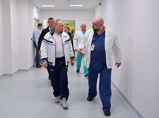 Russian President Vladimir Putin, center, and the hospital's chief Denis Protsenko, right, walk in to the hospital for coronavirus patients in Kommunarka settlement, outside Moscow, Russia, Tuesday, March 24, 2020. During a visit to the Komunarka hospital on Moscow outskirts, Putin praised its doctors for high professionalism, saying they were working &quot;like clockwork.&quot;  For some people the COVID-19 coronavirus causes mild or moderate symptoms, but for some it can cause severe illness including pneumonia. (Alexei Druzhinin, Sputnik, Kremlin Pool Photo via AP)
