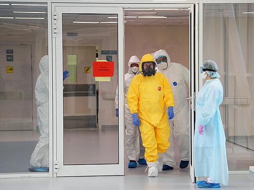 Russian President Vladimir Putin, center right, wearing a protective suit enters a hall during his visit to the hospital for coronavirus patients in Kommunarka settlement, outside Moscow, Russia, Tuesday, March 24, 2020.  For some people the COVID-19 coronavirus causes mild or moderate symptoms, but for some it can cause severe illness including pneumonia. (Alexei Druzhinin, Sputnik, Kremlin Pool Photo via AP)