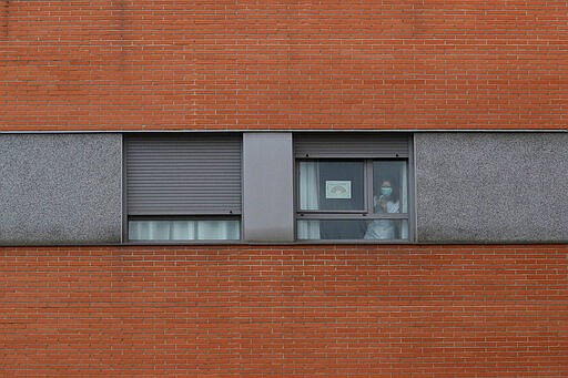 A nurse looks out from a window inside of a nursing homes where dead bodies were found at the nursing homes of Usera in Madrid, Spain, Tuesday, March 24, 2020.  Spanish army troops disinfecting nursing homes have found, to their horror, some residents living in squalor among the infectious bodies of people that authorities suspect have died from the new coronavirus. Prosecutors have launched a judicial probe. For some, it can cause more severe illness, especially in older adults and people with existing health problems. (AP Photo/Manu Fernandez)