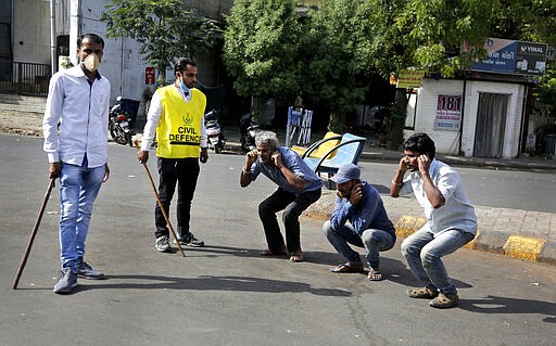 An Indian policeman, left and a civil defense person, second left, make people perform sit ups while holding their ear lobes, as a punishment for stepping out without a valid reason during a lockdown in Ahmedabad, India, Tuesday, March 24, 2020. Authorities have gradually started to shutdown much of the country of 1.3 billion people to contain the outbreak. For most people, the new coronavirus causes only mild or moderate symptoms. For some it can cause more severe illness. (AP Photo/Ajit Solanki)