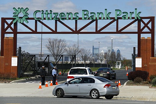 Cars enter a COVID-19 testing site near Citizens Bank Park, home to the Philadelphia Phillies baseball team, Tuesday, March 24, 2020, in Philadelphia. For most people, the new coronavirus causes only mild or moderate symptoms. For some it can cause more severe illness. (AP Photo/Matt Slocum)