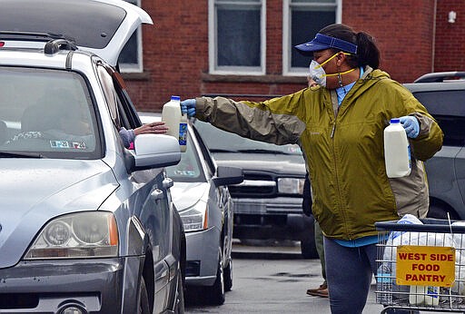 Rena Briggs hands milk over to a person in line at the Al Beech/West Side Food Pantry, Tuesday, March 24, 2020, in Kingston, Pa. Normally the pantry is set up like a store, but due to the coronavirus pandemic it is operating as a drive-thru pantry. (Aimee Dilger/The Times Leader via AP)