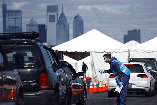 A healthcare worker talks with a patient at a COVID-19 testing site near Citizens Bank Park, home of the Philadelphia Phillies baseball team, Tuesday, March 24, 2020, in Philadelphia. For most people, the new coronavirus causes only mild or moderate symptoms. For some it can cause more severe illness. (AP Photo/Matt Slocum)