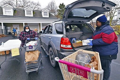 Joan, left, and her daughter Deja Spivey load food into a vehicle at the Al Beech/West Side Food Pantry, Tuesday, March 24, 2020, in Kingston, Pa. Normally the pantry is set up like a store, but due to the coronavirus pandemic it is operating as a drive-thru pantry. (Aimee Dilger/The Times Leader via AP)