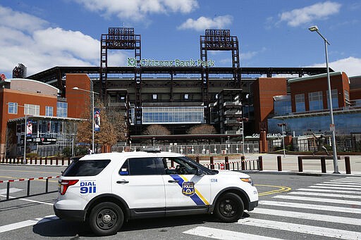 A Police vehicle blocks a street near Citizens Bank Park, home of the Philadelphia Phillies baseball team, Tuesday, March 24, 2020, in Philadelphia. The park is a temporary testing site for COVID-19. For most people, the new coronavirus causes only mild or moderate symptoms. For some it can cause more severe illness. (AP Photo/Matt Slocum)