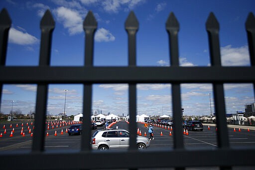 A healthcare worker directs a car at a COVID-19 testing site near Citizens Bank Park, home of the Philadelphia Phillies baseball team, Tuesday, March 24, 2020, in Philadelphia. For most people, the new coronavirus causes only mild or moderate symptoms. For some it can cause more severe illness. (AP Photo/Matt Slocum)