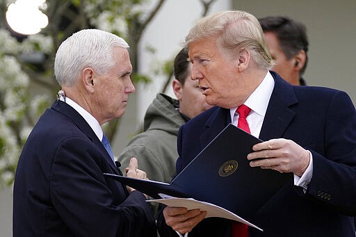 President Donald Trump speaks with Vice President Mike Pence as they arrive for a Fox News Channel virtual town hall, at the White House, Tuesday, March 24, 2020, in Washington. (AP Photo/Evan Vucci)